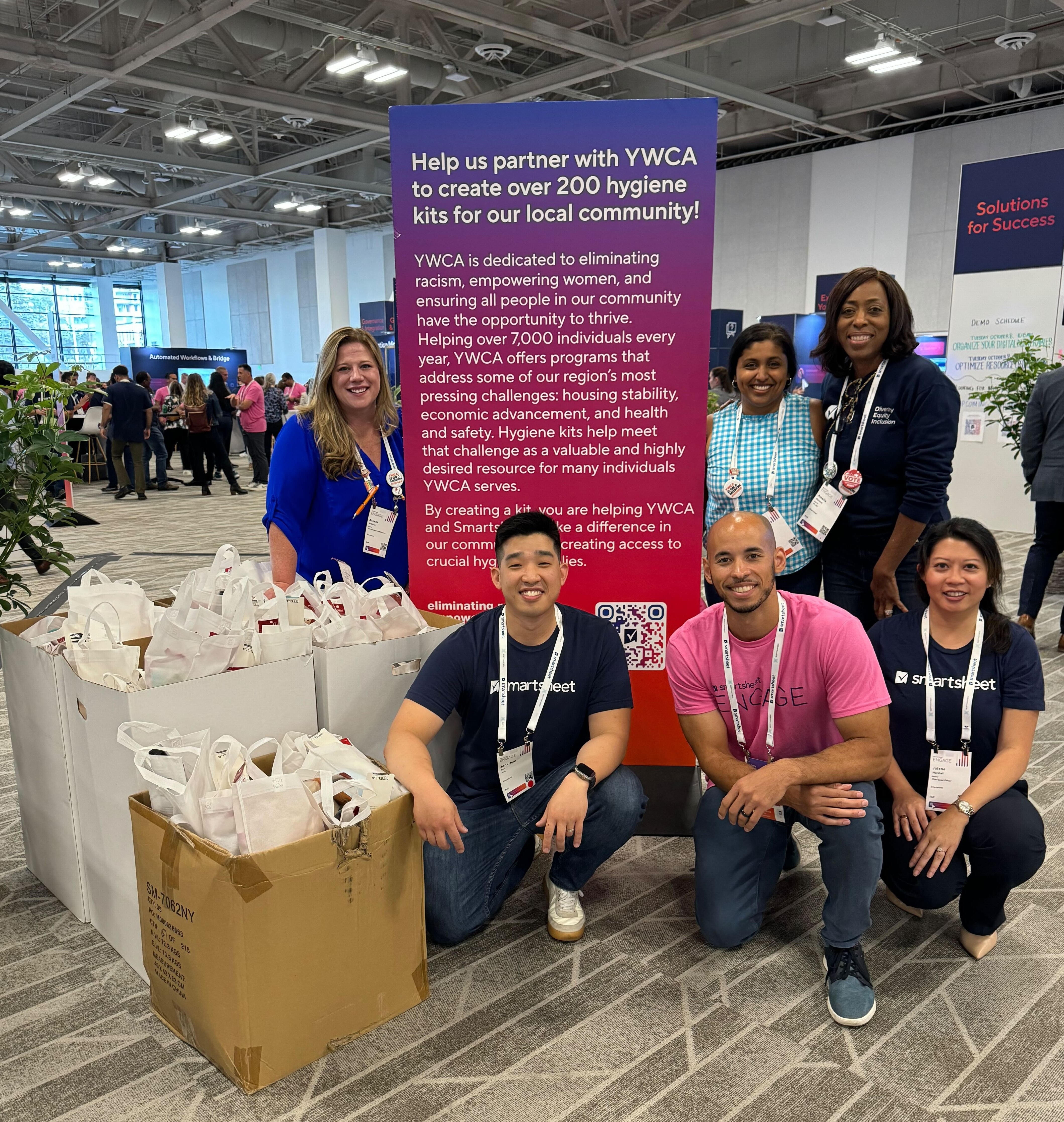 The Smartsheet DEI team poses with 200 assembled hygiene kits at Smartsheet ENGAGE 2024.