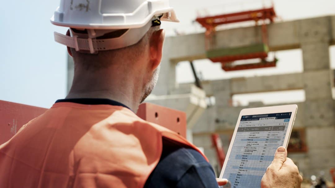 An on-site construction project manager uses Smartsheet on a tablet